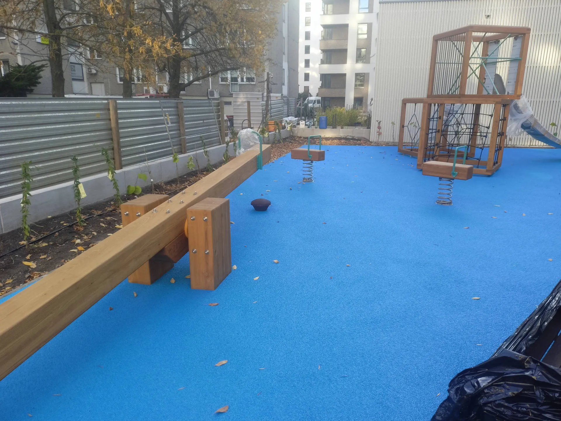Drewniane urządzenia placu zabaw na niebieskiej nawierzchni EPDM